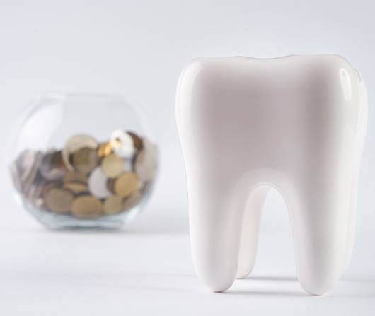 giant plastic tooth with bowl of coins in back