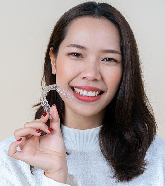 woman smiling bright holding invisalign tray