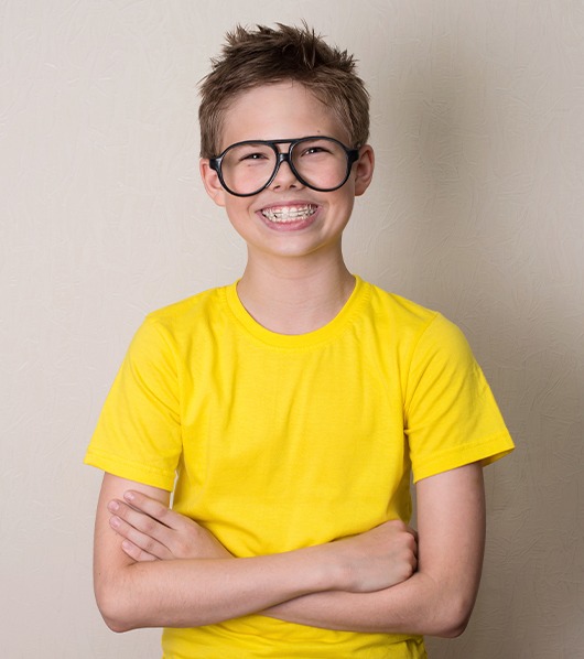 young boy in yellow shirt smiling big with braces