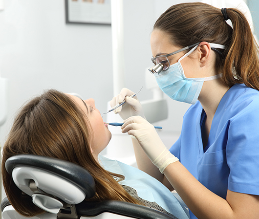 Orthodontist working on brunette woman's smile