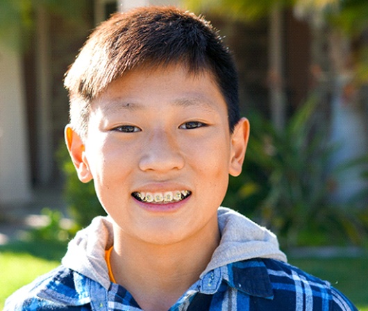 A young boy wearing metal braces to bring his smile into proper alignment