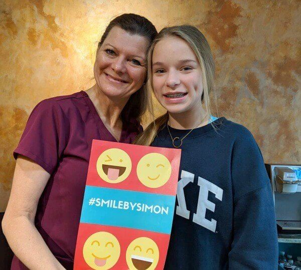 Dallas team member and patient with #smilebysimon sign