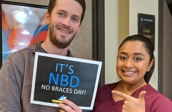Dallas team member and patient with No braces day sign