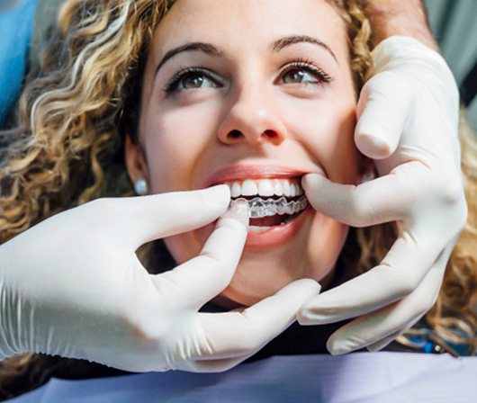 Dallas orthodontist placing Invisalign aligners on patient