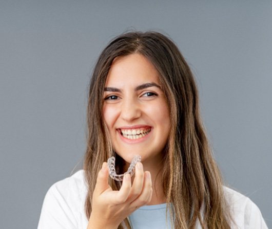 Patient in white shirt smiling with Invisalign in Dallas