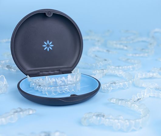 Carrying case for Invisalign in Dallas, TX surrounded by aligners