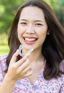 smiling woman holding invisalign braces
