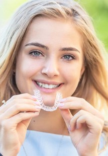 smiling woman holding invisalign braces