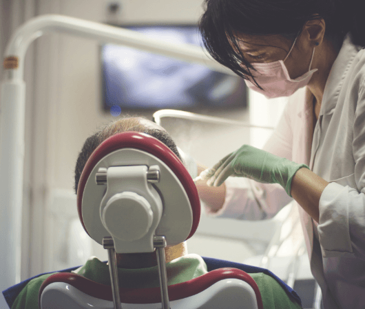 Dentist working on patient in red dentistry treatment chair