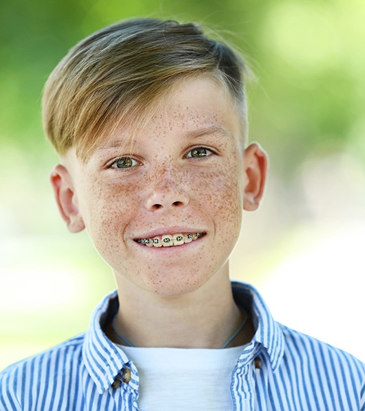 boy with freckles and metal braces smiling