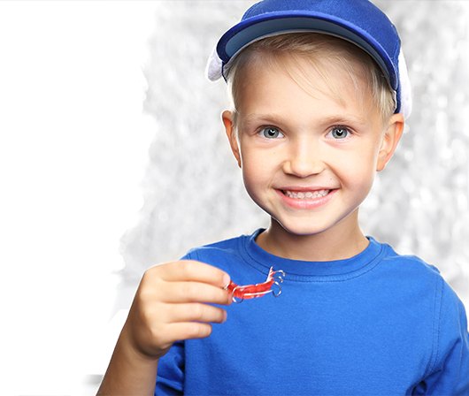 young boy in blue holding retainer