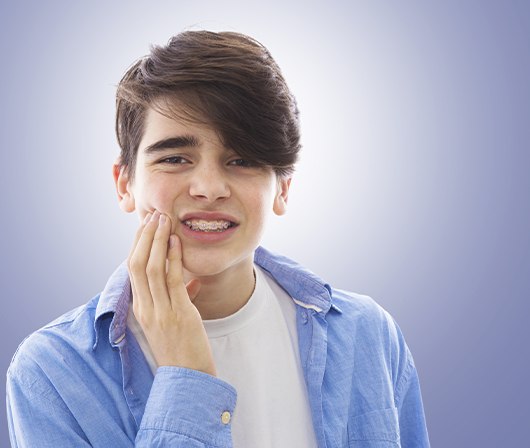 boy with braces gritting teeth in pain