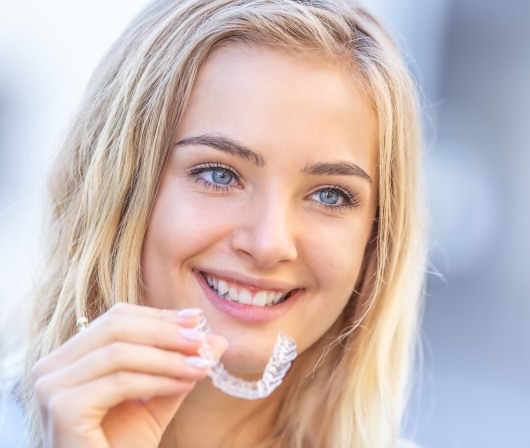 blonde woman holding invisalign