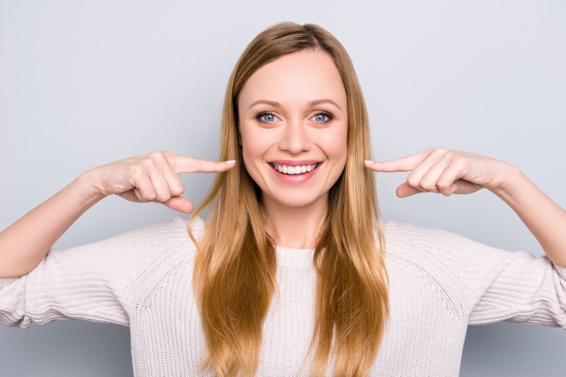 Smiling woman pointing to her straight teeth