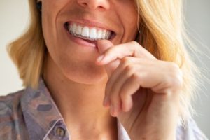 a smiling person putting their Invisalign aligners in their mouth