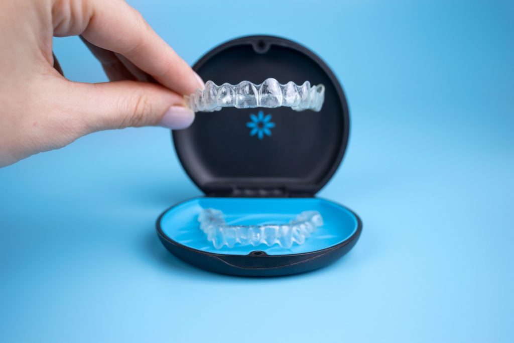 Patient placing Invisalign aligner in storage case